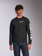 T-shirt à manches longues Alpinestars Trackside CSF, noir, logo Alpinestars blanc sur la poitrine et lettrage sur la manche, porté par un mannequin avec un jean bleu, style streetwear décontracté motorsport