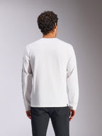 T-shirt à manches longues Alpinestars Trackside CSF, blanc, vue de dos sur mannequin, associé à un pantalon noir, tissu blanc épuré, style streetwear décontracté inspiré des sports mécaniques