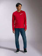 Alpinestars Trackside CSF Tee, t-shirt à manches longues, rouge avec logo Alpinestars blanc, photo lifestyle porté avec un jean bleu et des baskets noires, sportswear décontracté inspiré du sport automobile