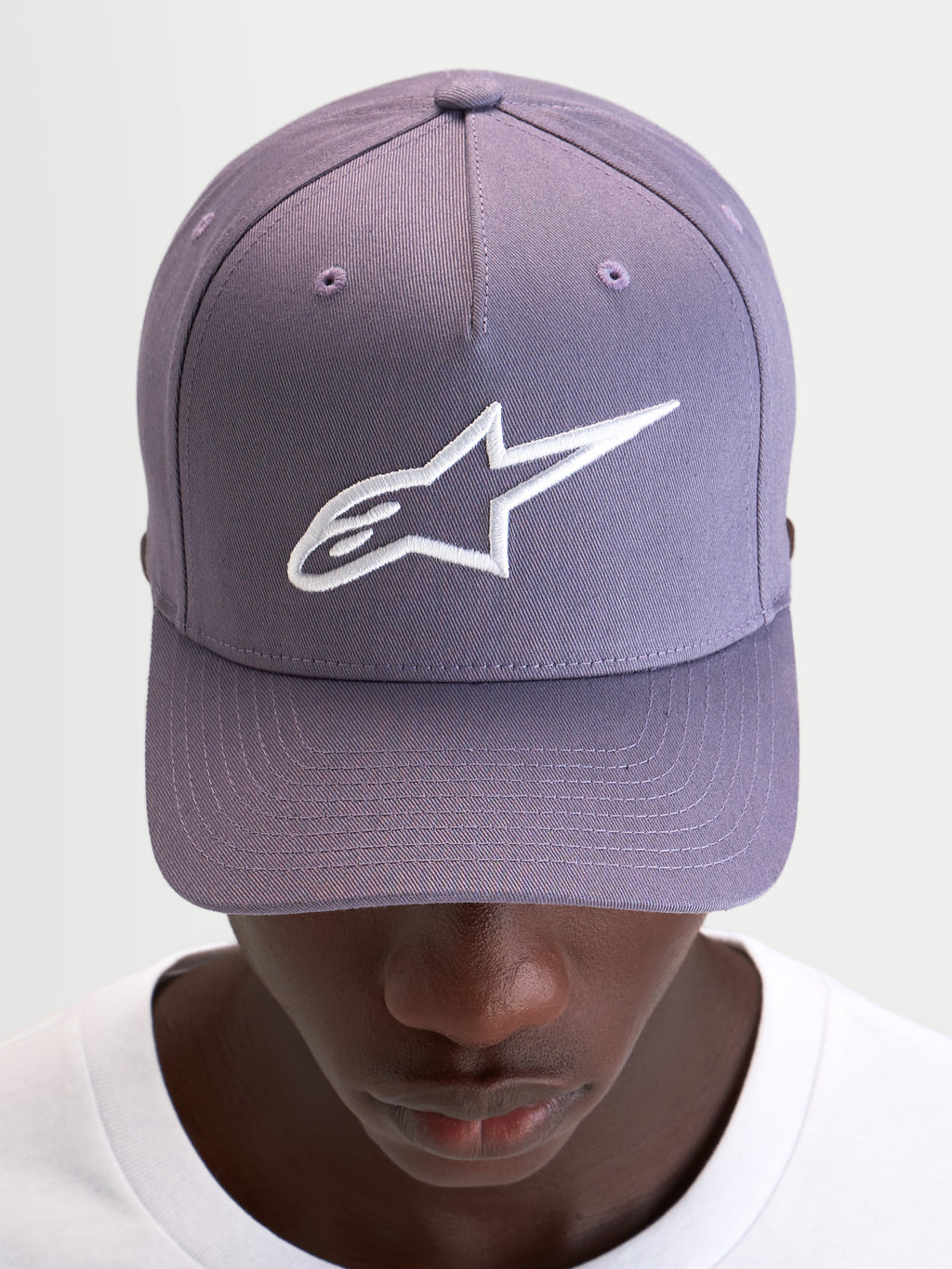 Alpinestars Casquette Snapback Ageless, casquette sportswear violette et blanche, couronne structurée et logo Astars brodé en 3D sur l'avant, portée par un modèle