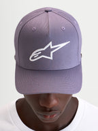 Alpinestars Casquette Snapback Ageless, casquette sportswear violette et blanche, couronne structurée et logo Astars brodé en 3D sur l'avant, portée par un modèle