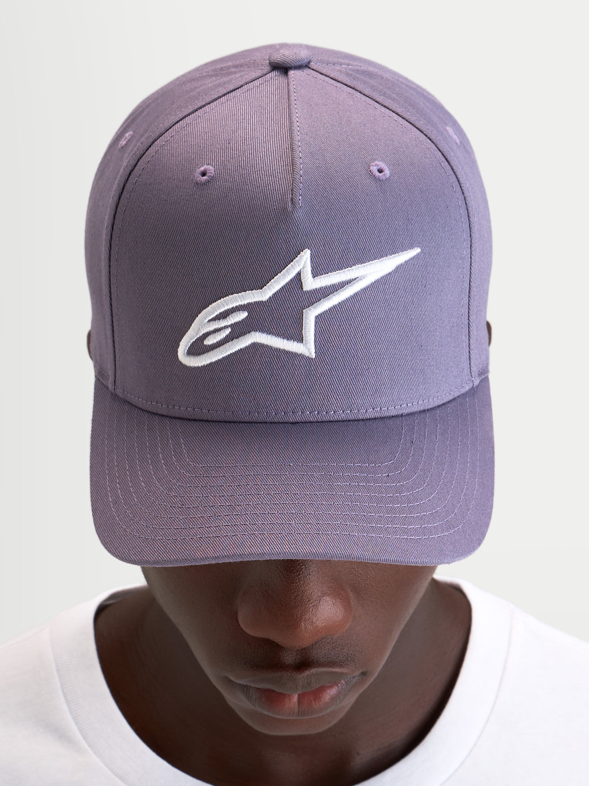Alpinestars Casquette Snapback Ageless, casquette sportswear violette et blanche, couronne structurée et logo Astars brodé en 3D sur l'avant, portée par un modèle