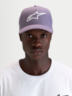 Alpinestars Casquette Snapback Ageless, casquette sportswear violette et blanche, portée par un modèle mettant en valeur le logo Astars brodé 3D sur l'avant et le profil structuré