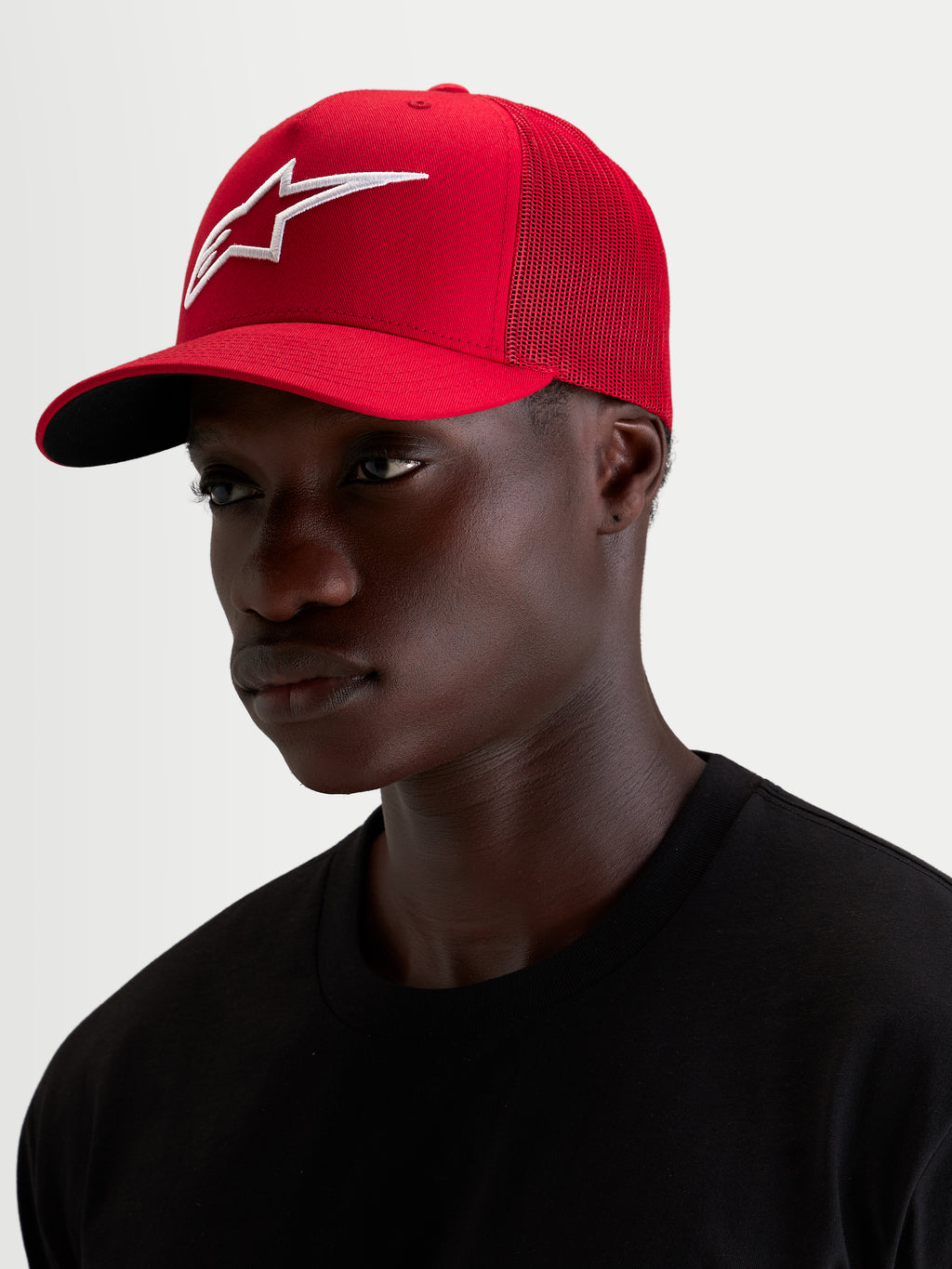 Alpinestars Casquette Snapback Ageless, casquette sportswear rouge et blanche portée par un modèle, avec visière incurvée et logo 3D brodé