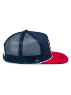 Casquette Trucker Control Alpinestars, bleu marine et rouge, vue de profil montrant l'avant en sergé bleu marine et les panneaux arrière en maille, visière plate rouge avec détail de cordelette tressée blanche, couvre-chef décontracté d'inspiration sport automobile