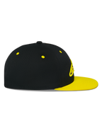Casquette Snapback Alpinestars Thickness, vue de profil, couronne noire avec visière plate et œillets jaune haute visibilité, logo brodé en 3D à l'avant, couvre-chef décontracté inspiré du sport automobile