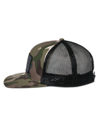 Casquette Trucker Alpinestars Flag Flat, camouflage vert et noir, visière plate et couronne structurée, avant en sergé camouflage avec arrière en maille noire, vue latérale montrant le patch drapeau merrow et le logo brodé, streetwear décontracté inspiré du sport automobile