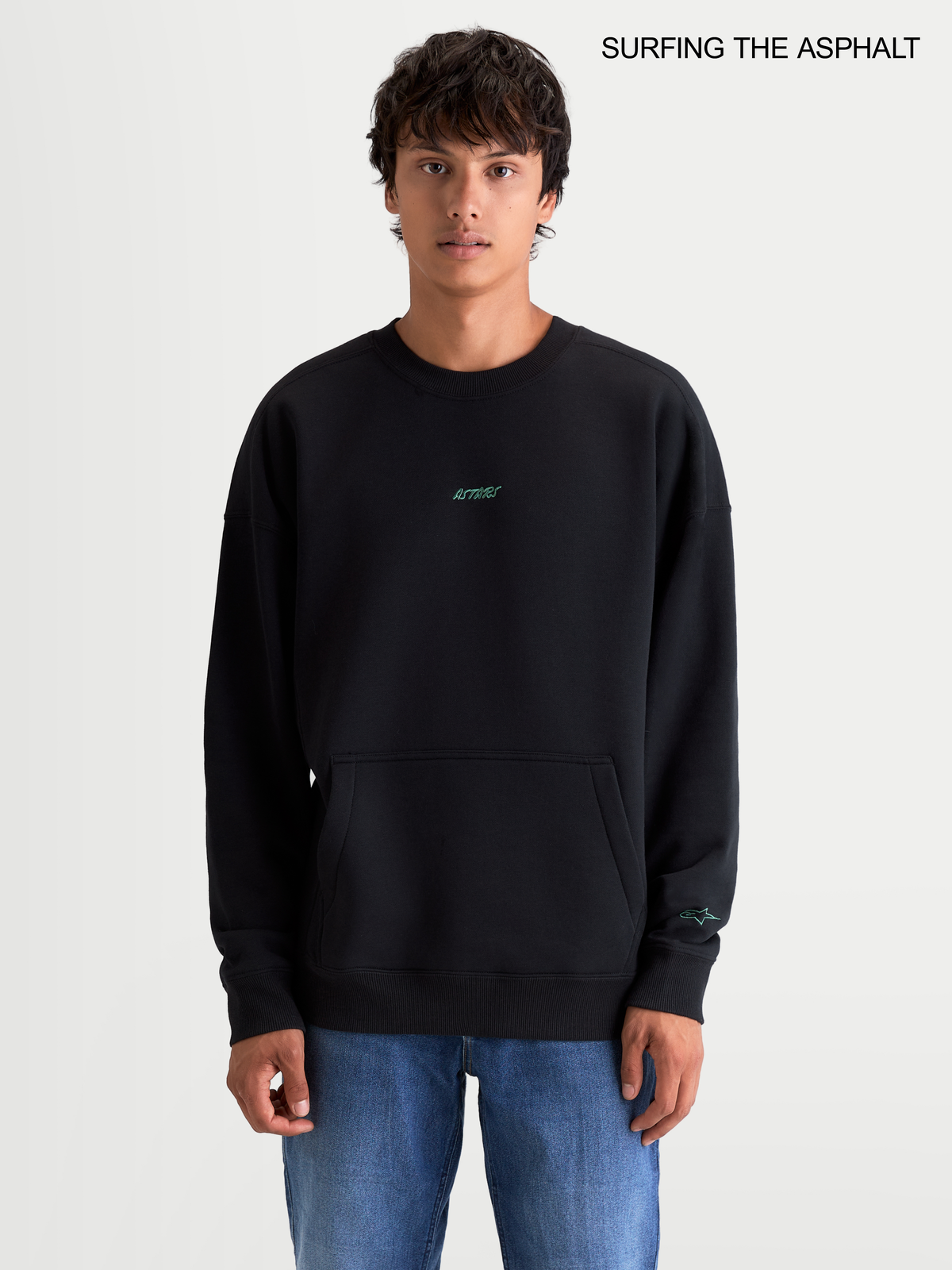 Alpinestars Guise Oversized Crew, sweat-shirt sportswear noir pour homme, coupe ample et décontractée avec col ras du cou, poche kangourou et logo brodé, porté par un modèle