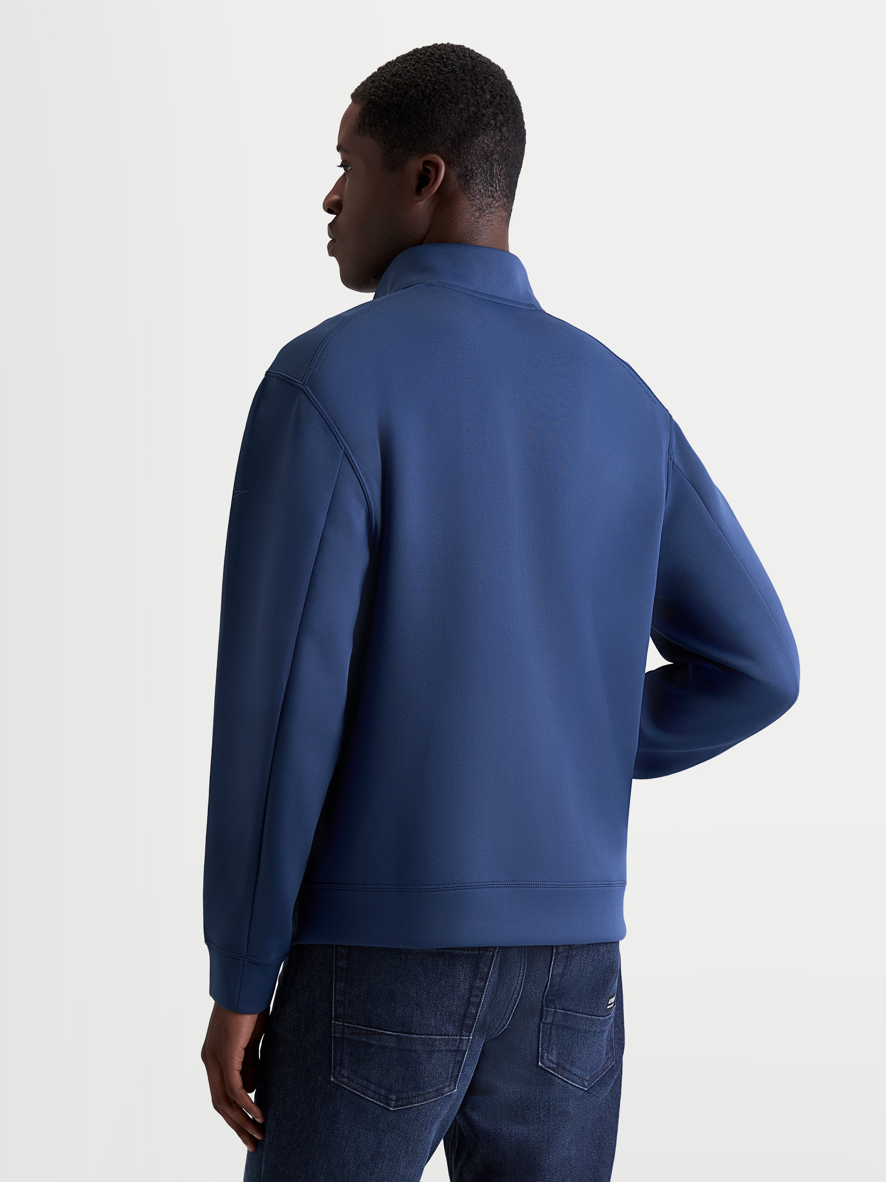 Sweat Apera Half-Zip Alpinestars, pull sportswear pour homme, bleu acier, construction en polaire double face tri-mélange, vue de dos sur un modèle montrant les coutures de manches raffinées et le design épuré inspiré du sport automobile.