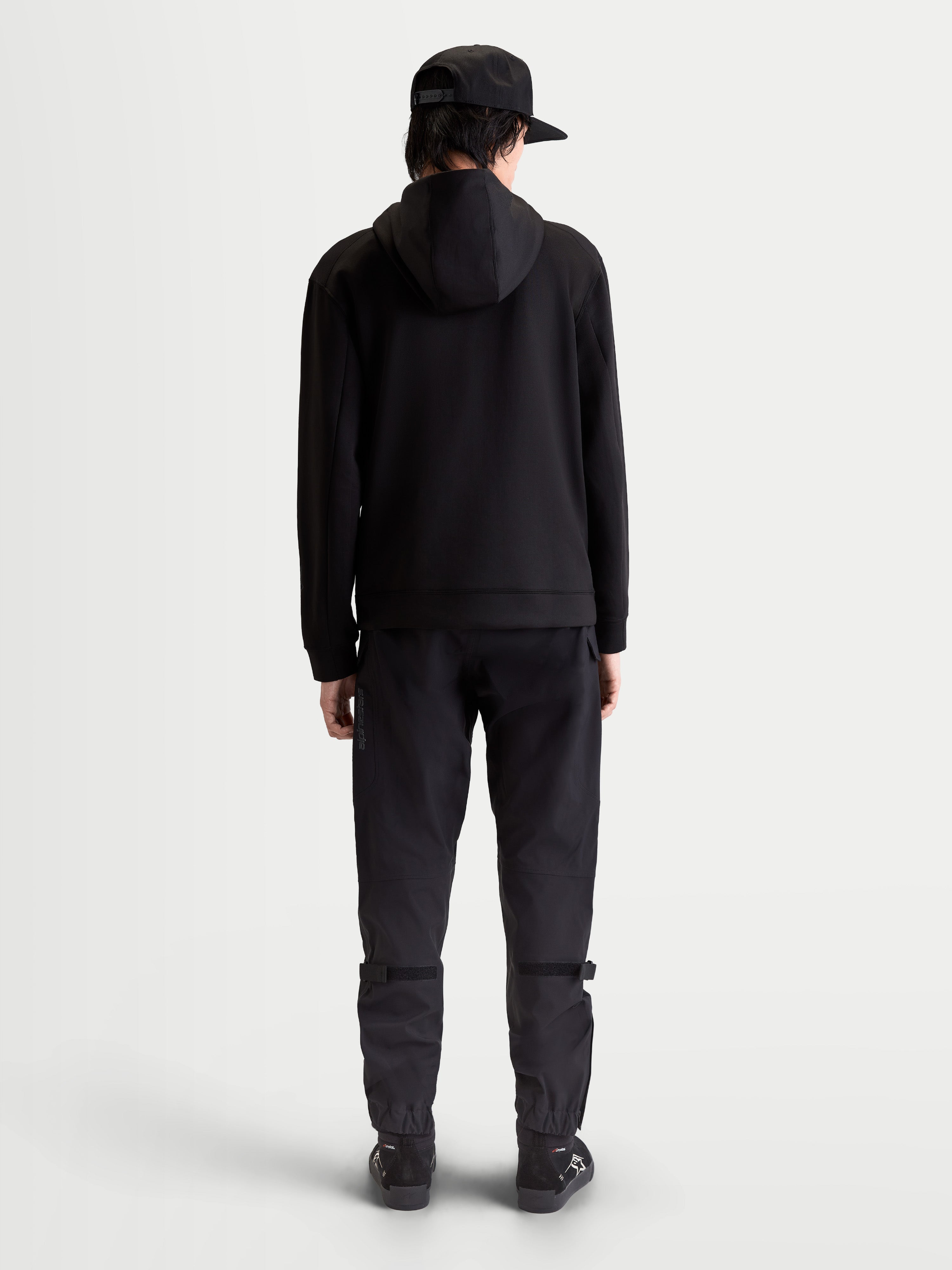 Alpinestars Sweat à capuche Datrix, sweat sportswear premium, noir, vue de dos sur modèle, polaire double face tri-mélange avec capuche doublée en mesh, style épuré inspiré du sport automobile.