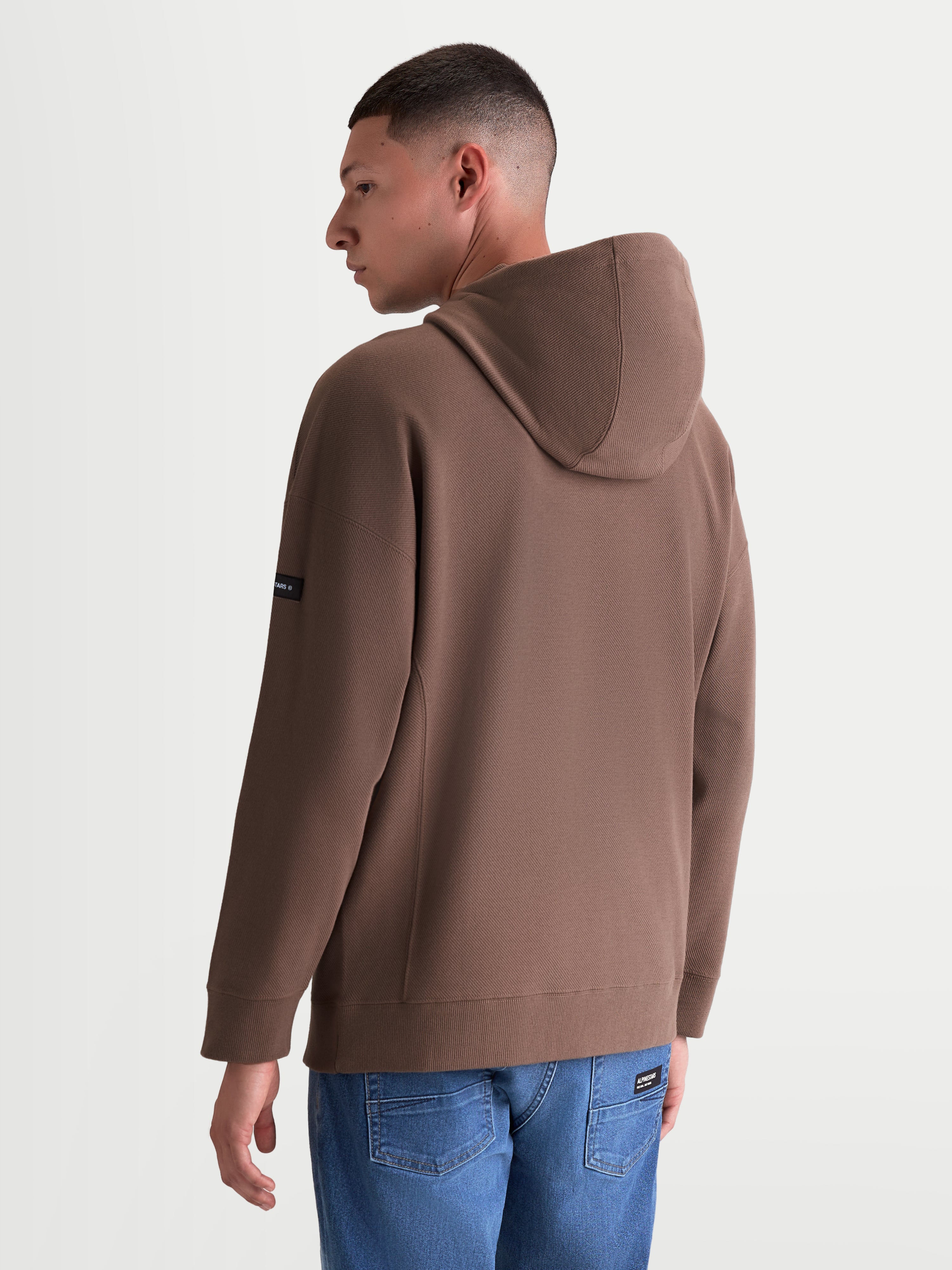 Alpinestars Camino Textured Oversized Hoodie, sweat à capuche de sportswear décontracté pour homme et femme, marron, polaire texturée en maille sergée, vue de dos avec coupe ample et marquage sur la manche.