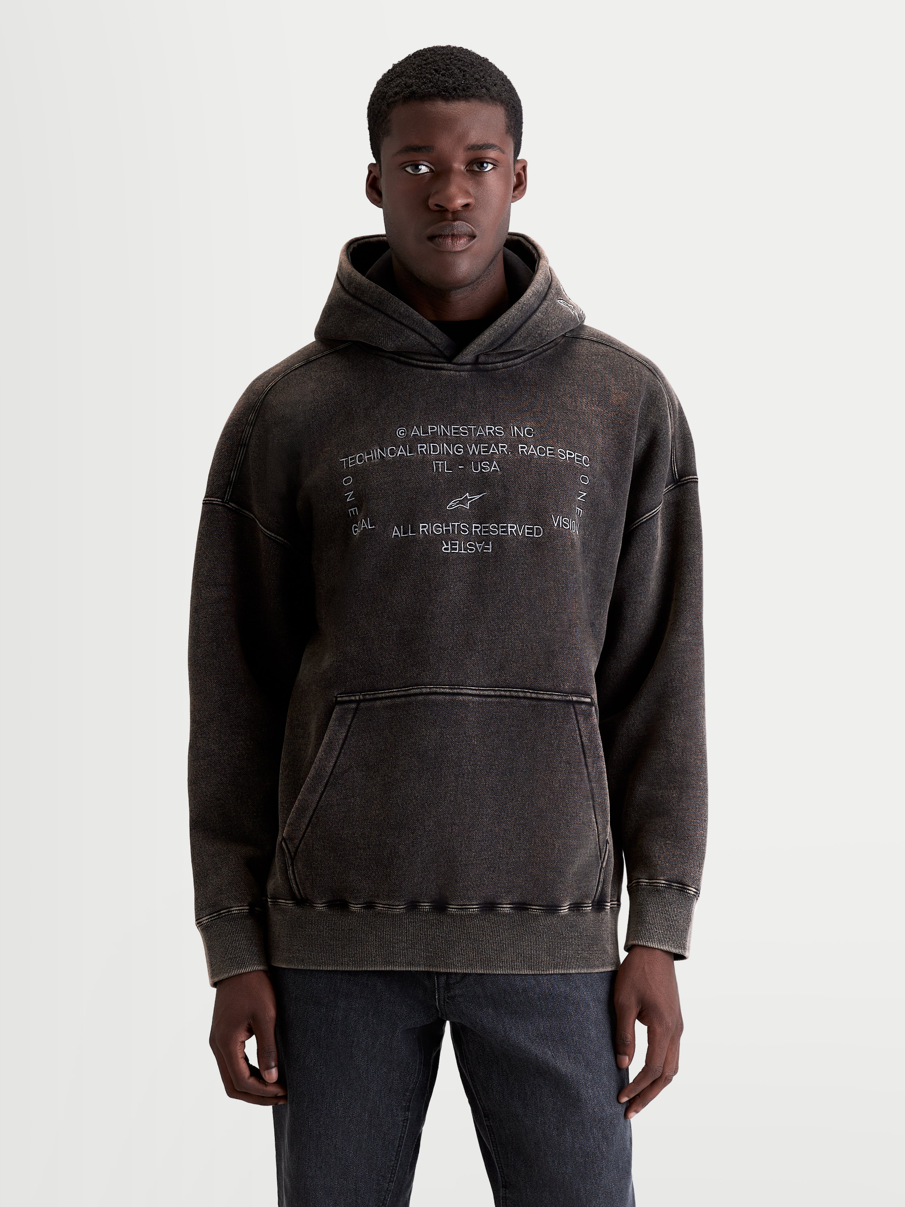 Alpinestars Sweat à capuche Infinite Washed Oversize, sweat à capuche sportswear décontracté, noir délavé, polaire avec finition effet neige, poche kangourou et texte du logo Alpinestars brodé en blanc, vue de face sur modèle
