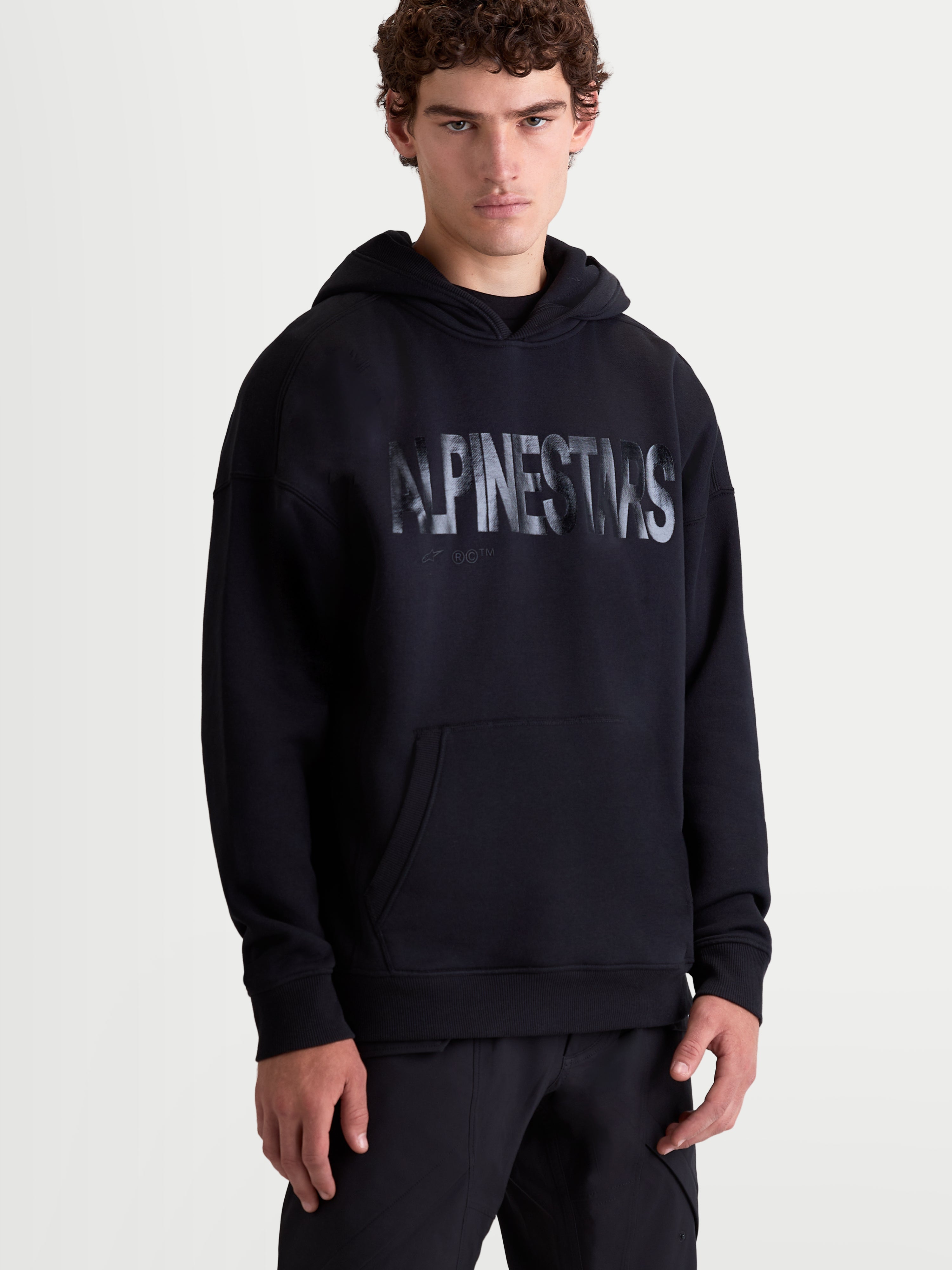 Alpinestars Shaw Oversized Hoodie, Sportswear Pullover for Men and Women, Black with a bold textured Alpinestars logo, Cotton blend fleece, featuring a kangaroo pocket and relaxed fit.