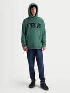 Alpinestars sweat à capuche Shaw Oversized, sweat à capuche sportswear décontracté, vert avec logo texturé noir, vue de face sur modèle, polaire douce en coton et polyester recyclé avec poche kangourou