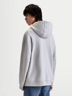 Alpinestars sweat à capuche Prelude Oversized, sweat à capuche sportswear en polaire pour homme et femme, gris ciment, vue de dos sur mannequin, silhouette décontractée avec coutures aux manches et capuche doublée.