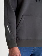 Alpinestars Sweat à capuche Prelude Oversized, sweat de sport en polaire gris anthracite, vue détaillée des coutures de la manche, poignet côtelé et logo Alpinestars blanc sur le bras, coupe décontractée avec poche kangourou.