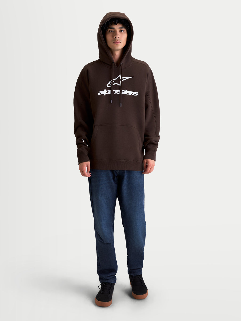 Alpinestars Prelude Oversized Hoodie, sweat à capuche sportswear en polaire unisexe, marron, matière riche en coton, coupe décontractée oversized, logo blanc en relief sur la poitrine, poche kangourou et capuche doublée, présenté sur un modèle