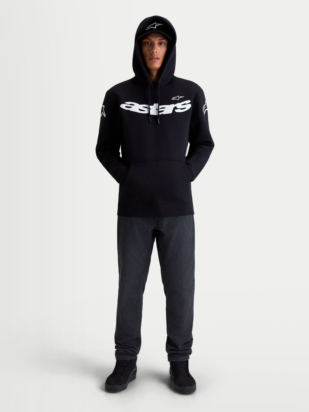 Alpinestars Sweat À Capuche Velocifier, sweat à capuche de sportswear, noir et blanc, mélange de coton et polyester recyclé, avec logo Astars sur la poitrine et logos sur les épaules, vu de face sur modèle pour un style décontracté hors moto