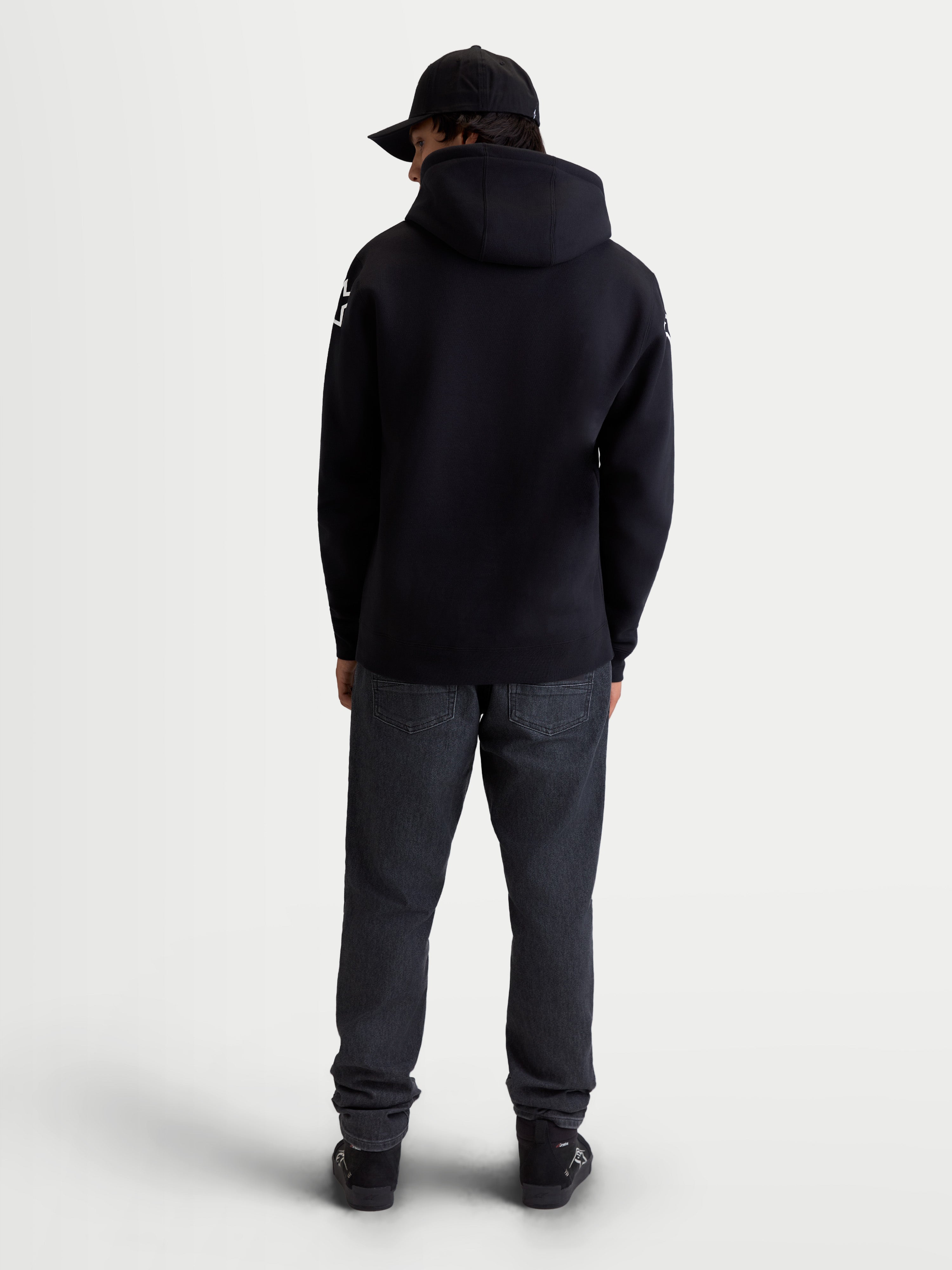Alpinestars Velocifier, sweat à capuche de sportswear pour homme en polaire, noir, mélange de coton et polyester recyclé, vue de dos sur modèle montrant la capuche et les logos Alpinestars blancs sur les épaules.