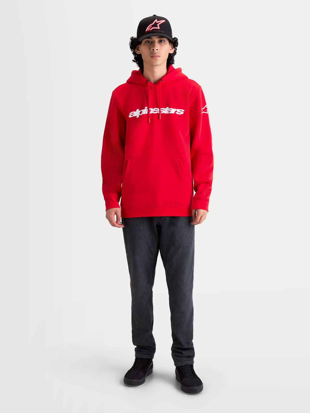Alpinestars Sweat À Capuche Race Wordmark, sweat à capuche de sportswear en polaire rouge avec logo wordmark Alpinestars blanc, doté d'une poche kangourou et d'une capuche à cordon de serrage, porté par un modèle pour un style motorsport décontracté.