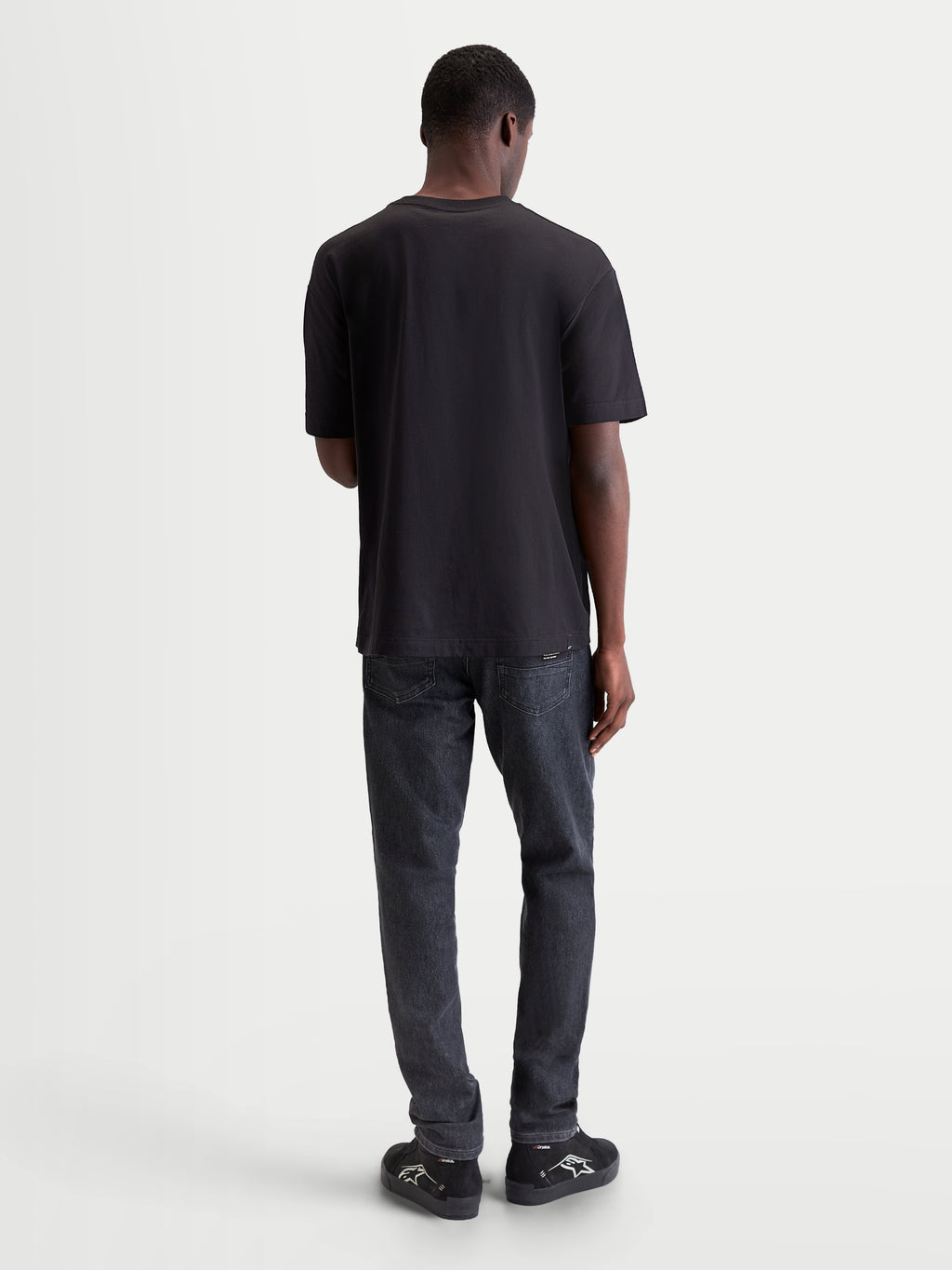 Alpinestars Infinity Oversized CSF, t-shirt de sportswear à manches courtes, noir, coupe oversize décontractée, vue de dos sur modèle, style lifestyle et confort quotidien hors moto