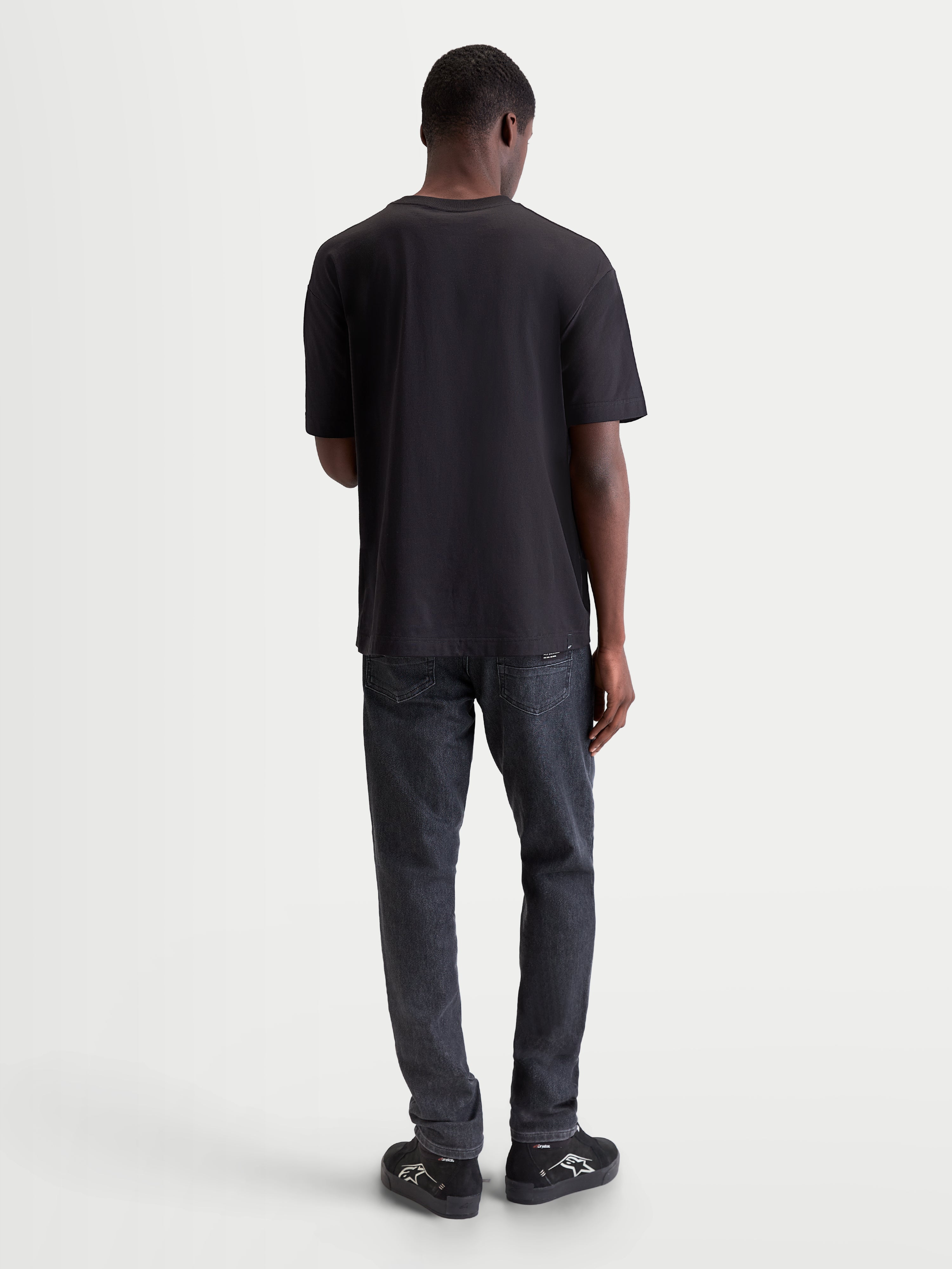 Alpinestars Infinity Oversized CSF, t-shirt de sportswear à manches courtes, noir, coupe oversize décontractée, vue de dos sur modèle, style lifestyle et confort quotidien hors moto