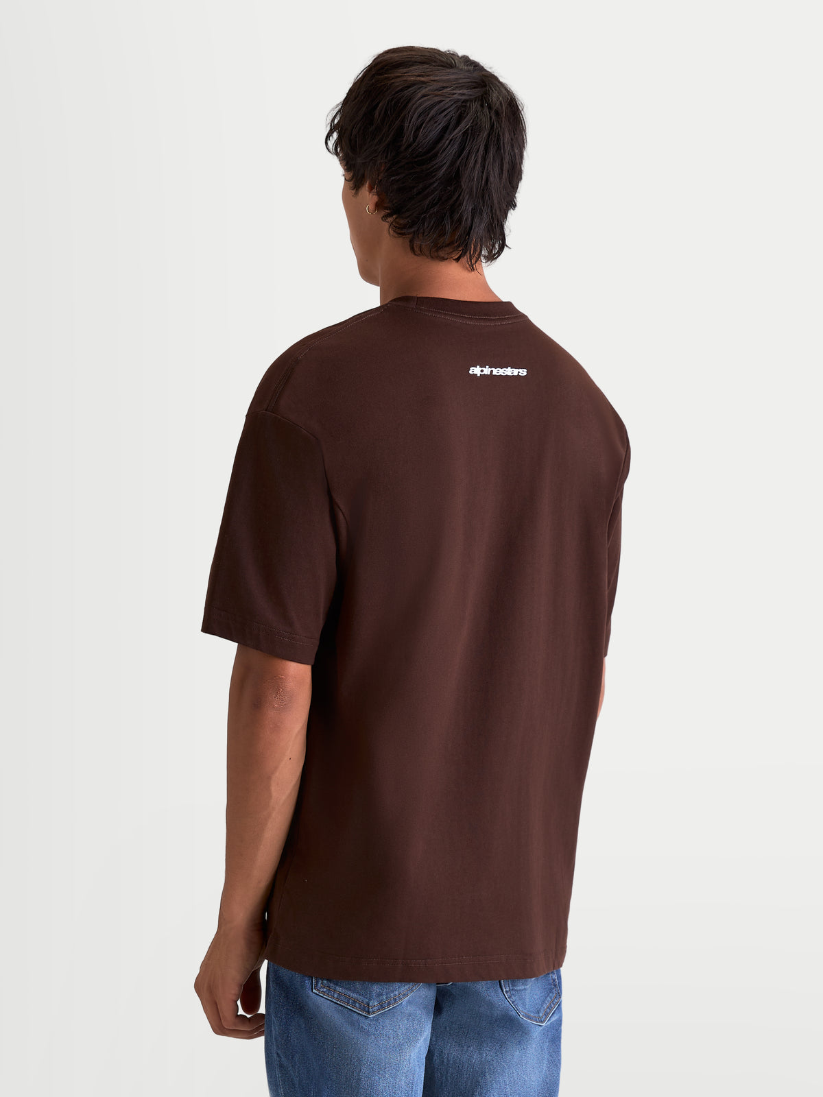 Alpinestars Prelude Oversized CSF Tee, Brown Short Sleeve Sportswear T-Shirt, Rear View on Model with White Alpinestars Wordmark Graphic on Upper Back, Relaxed Oversized Fit.