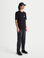 Alpinestars Meteor CSF, t-shirt de sportswear à manches courtes pour homme, noir avec logo blanc dégradé sur la poitrine, style motorsport décontracté, porté par un modèle
