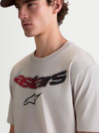 Alpinestars Elliptogrit CSF, t-shirt de sportswear à manches courtes pour homme, gris ciment, porté par un modèle, graphique Astars incurvé avec dégradé rouge et noir, style motorsport décontracté