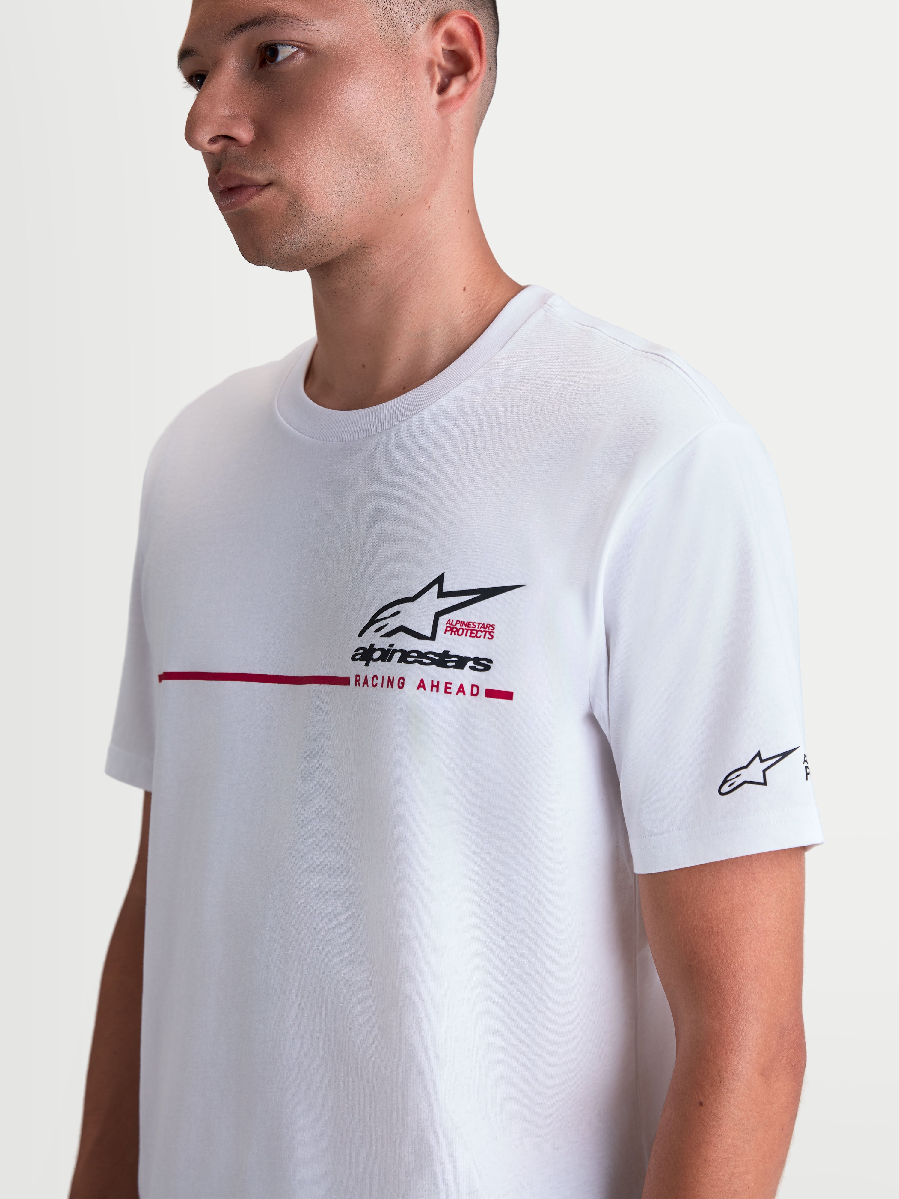 Alpinestars T-Shirt P1 CSF, t-shirt à manches courtes blanc porté par un modèle, graphisme logo Astars noir et rouge avec bande de course sur la poitrine, style sportswear motorsport décontracté