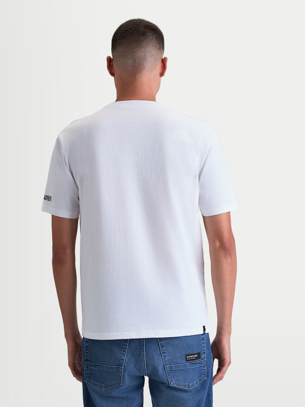 Alpinestars T-Shirt P1 CSF, t-shirt de sportswear à manches courtes pour homme, blanc, vue de dos sur modèle, vêtement de style motorsport décontracté