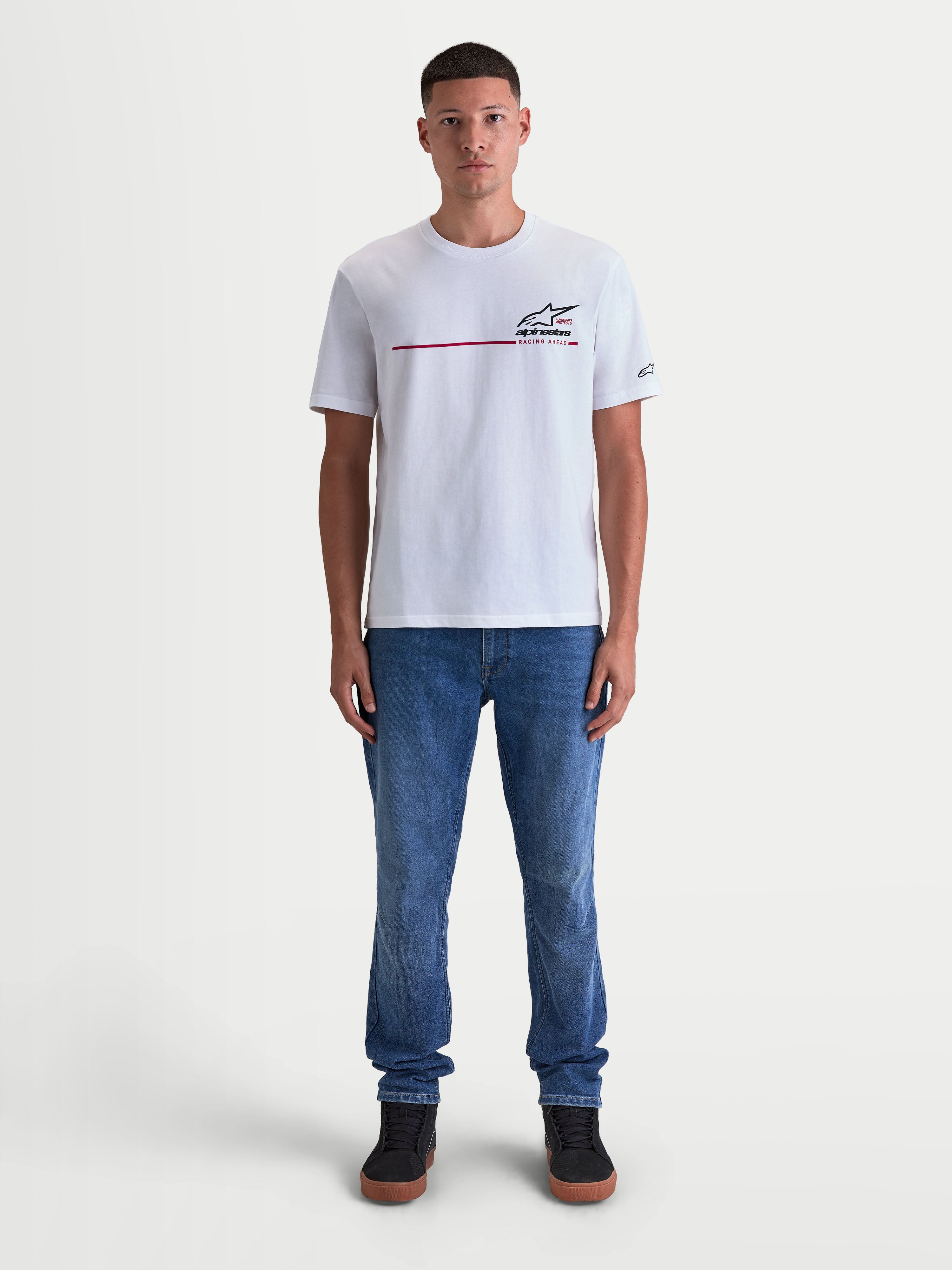 Alpinestars P1 CSF, t-shirt à manches courtes pour homme, blanc avec logo à bande de course motorsport, mélange coton et polyester, style sportswear décontracté porté par un modèle avec un jean.