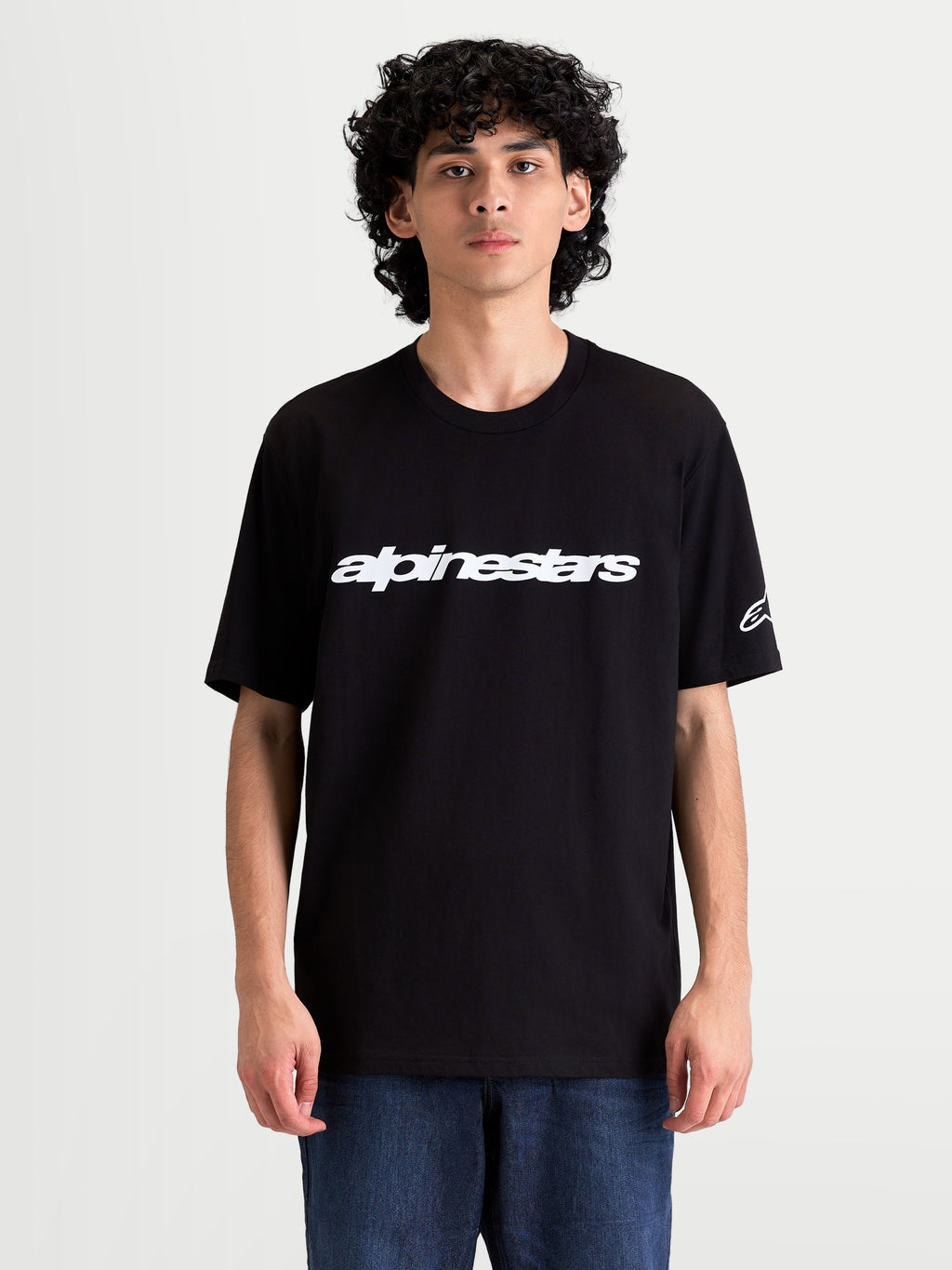 Alpinestars T-shirt Race Wordmark CSF, t-shirt sportswear à manches courtes pour homme, noir et blanc, porté par un modèle, avec graphique frontal audacieux et logo Ageless sur la manche.