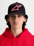 Alpinestars Lineout, casquette de style sportswear, noire avec logo Astars brodé rouge et blanc et slogan One Goal One Vision, couronne structurée et visière incurvée, vue de face sur un modèle portant un sweat à capuche rouge, construction en sergé