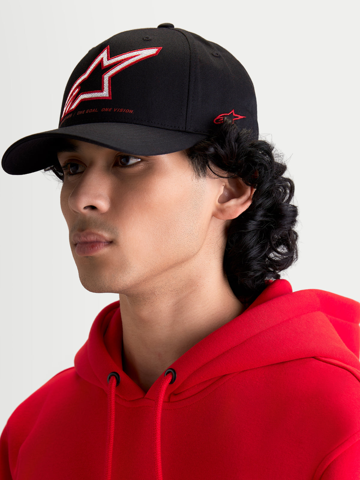 Alpinestars casquette Lineout, casquette de baseball sportswear noire, visière incurvée, couronne structurée avec logo Astars brodé rouge et blanc et marquage latéral, portée par un modèle.