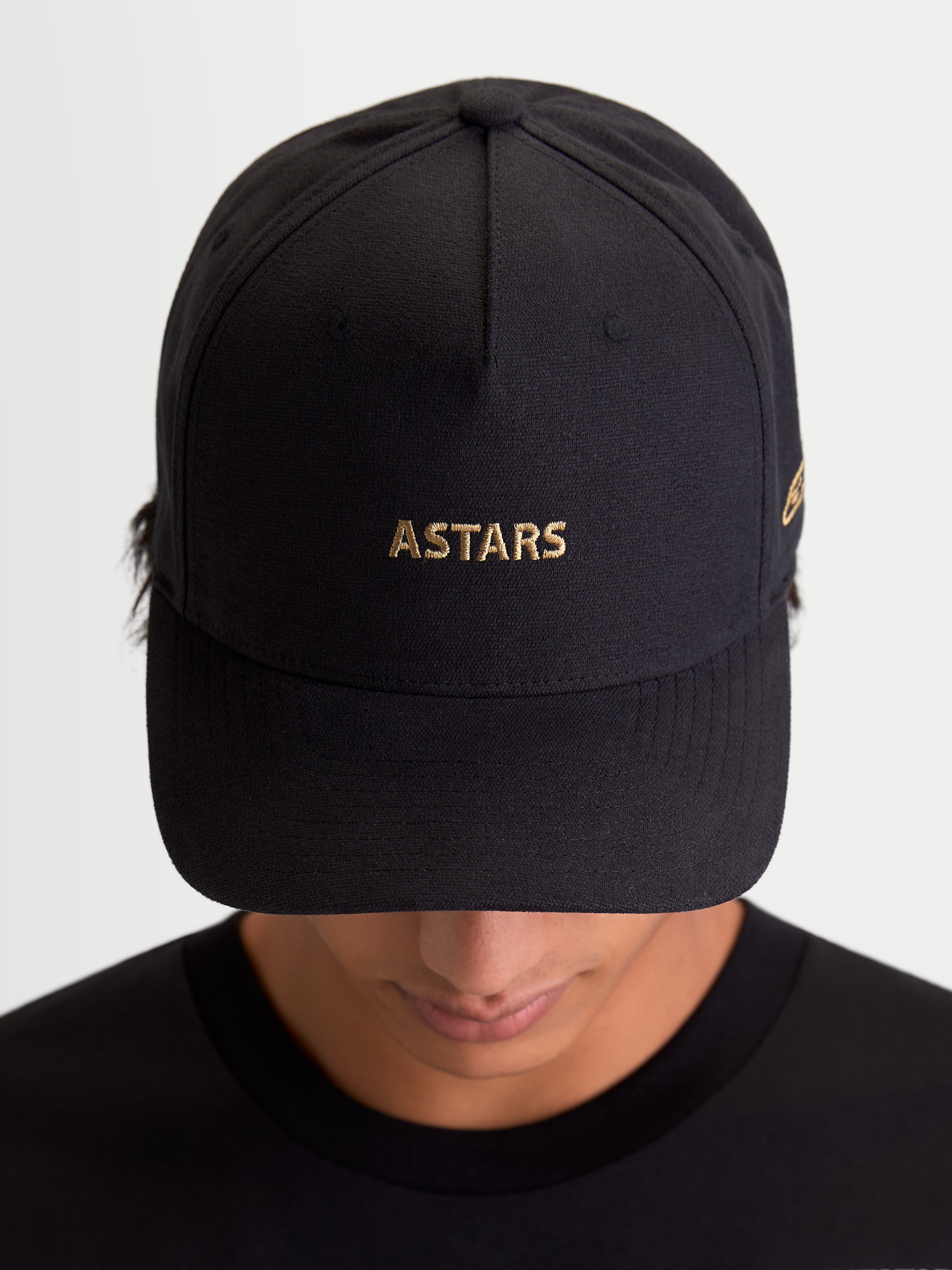 Alpinestars County Canvas Hat, Black Sportswear Cap with Gold ASTARS Logo Embroidery, Curved Bill and Structured Crown, Unisex Everyday Motorsport-Inspired Hat, Oxford Peached Fabric, Front View on Model