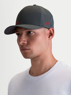 Alpinestars Casquette Points, casquette sportswear à visière incurvée portée par un modèle, gris foncé avec logos rouges, fabriquée en nylon tactel léger avec coupe flex-back pour un confort quotidien.