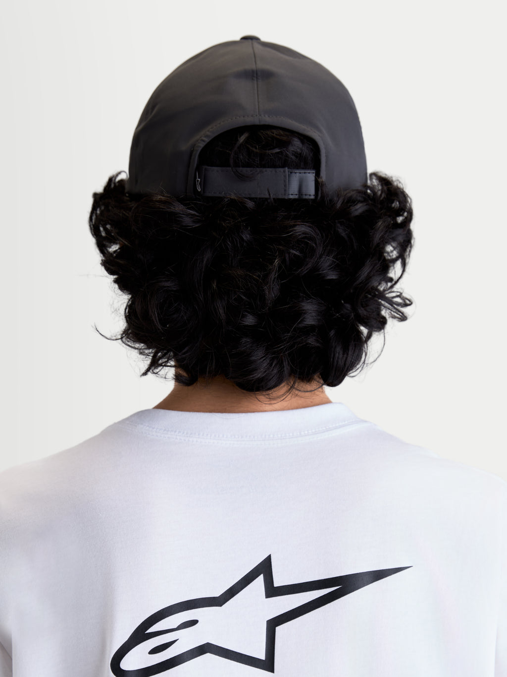 Alpinestars Casquette Réglable Algo Perf, casquette de sportswear grise foncée, construction en tissu technique avec fermeture arrière réglable, vue arrière sur modèle montrant la coupe et la couronne structurée