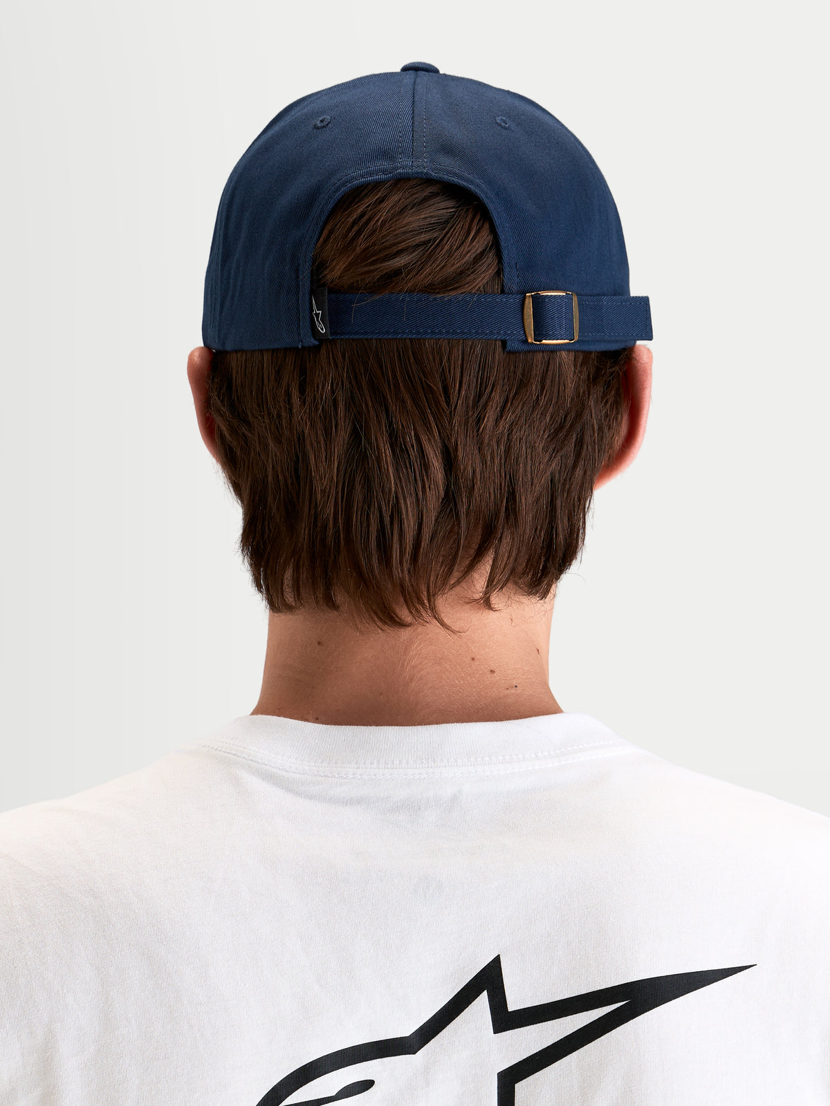 Alpinestars Dylan Dad Hat, casual sportswear cap in navy blue, rear view showing the adjustable strap-back closure with metal buckle and small Astars logo tag worn by a model