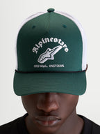 Alpinestars Casquette Baron Trucker, casquette sportswear verte et blanche, portée par un modèle, avec visière courbée, panneau avant structuré et logo brodé sur l'avant