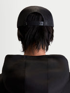 Alpinestars Casquette Trucker Gravel, casquette sportswear noire, vue de dos sur modèle montrant l'arrière en maille polyester respirante et la fermeture à pression réglable, style décontracté unisexe