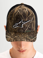 Casquette Trucker Thicket Realtree d'Alpinestars, casquette trucker sportswear portée par un modèle, camouflage Realtree et noir, visière courbée, couronne structurée et logo Astars brodé blanc sur le devant