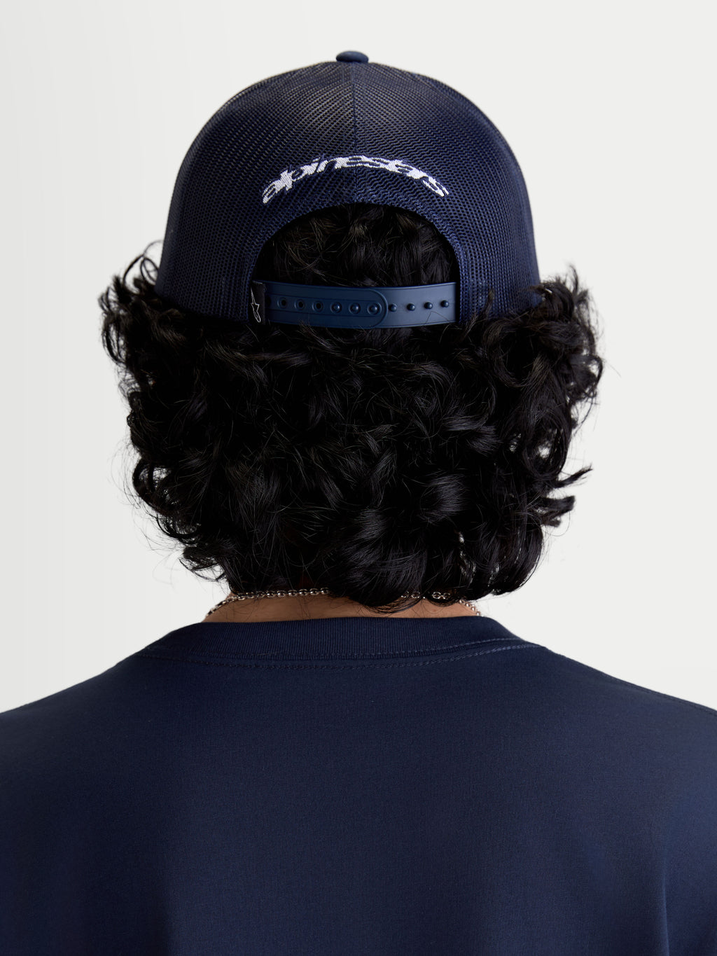 Alpinestars Casquette Trucker Meteorite, casquette de sportswear décontractée, vue de dos sur un modèle, bleu marine, arrière en maille polyester et fermeture snapback réglable avec logo brodé blanc