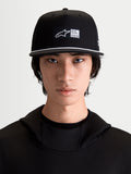 Alpinestars Label Snapback, casquette de sportswear pour homme, noire et blanche, visière plate avec détail de cordelette blanche, étiquette frontale tissée, en sergé de coton, vue de face sur modèle