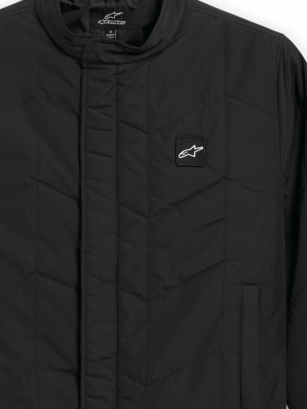 Alpinestars Precedent Jacket, veste de sport matelassée, noire, vue rapprochée présentant un motif matelassé en angle iconique, un col bas, une fermeture éclair avant couverte et un petit écusson logo sur la poitrine
