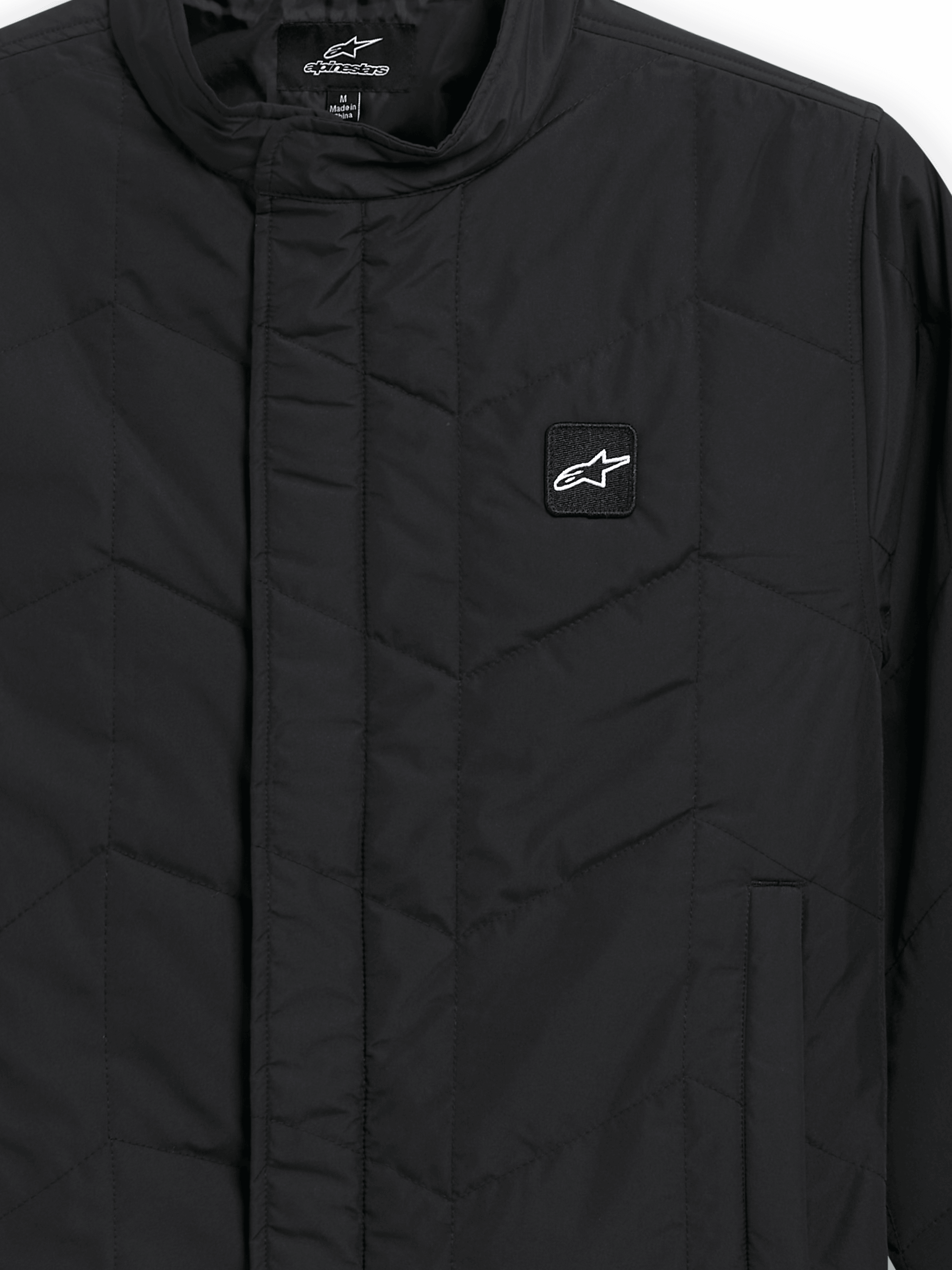 Alpinestars Precedent Jacket, veste de sport matelassée, noire, vue rapprochée présentant un motif matelassé en angle iconique, un col bas, une fermeture éclair avant couverte et un petit écusson logo sur la poitrine