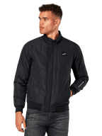 Alpinestars Precedent Jacket, veste matelassée noire avec motif en angle, style Formula 1, col bas, poignets et ourlet côtelés, écusson logo sur la poitrine, broderie sur la manche, streetwear lifestyle inspiré du sport automobile