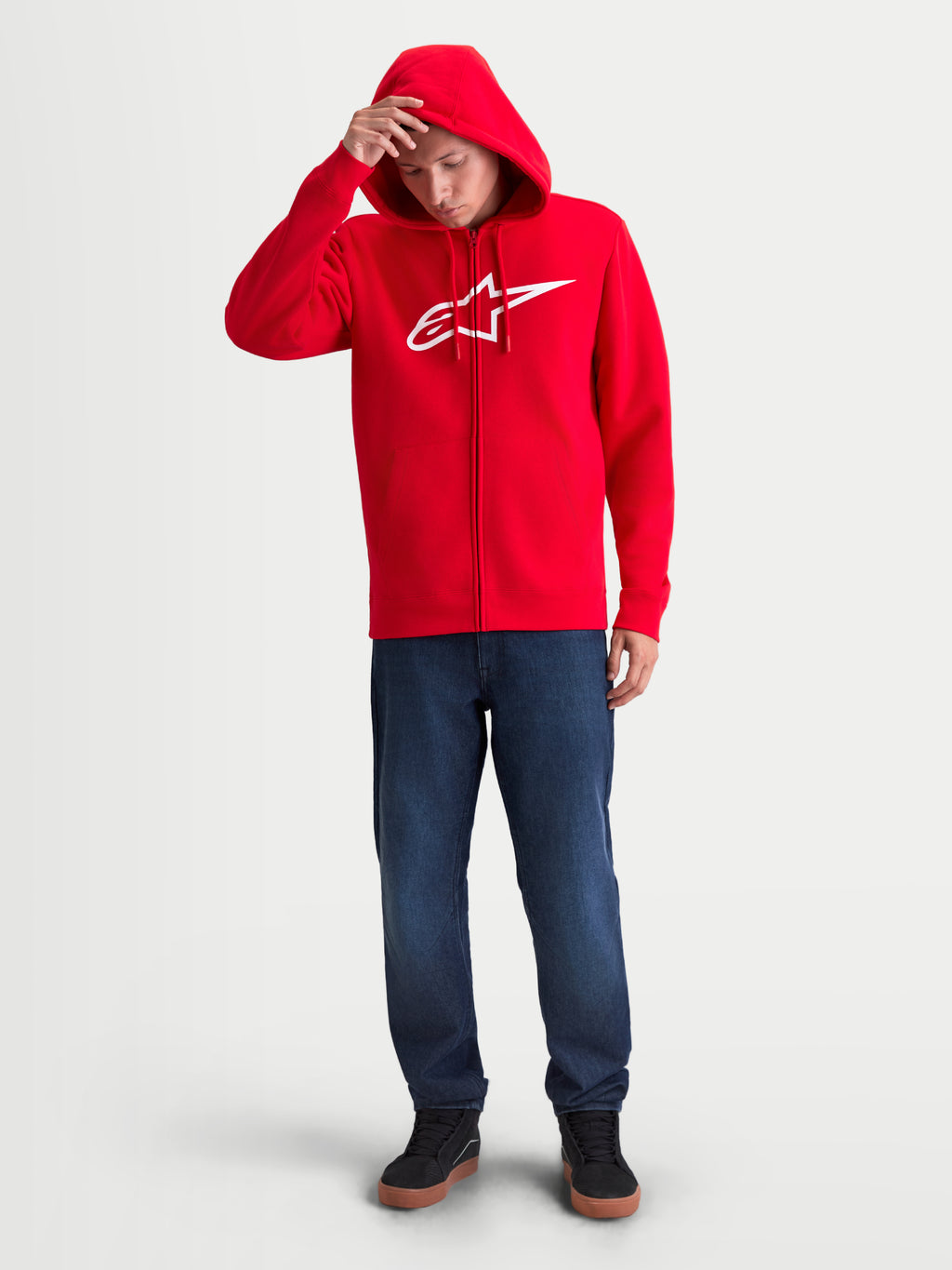 Alpinestars Sweat à capuche Ageless Zip V3, sweat de sportswear pour homme, rouge et blanc, porté par un modèle, avec logo Alpinestars blanc sur la poitrine, fermeture éclair intégrale et capuche à cordons. Style motorsport décontracté.