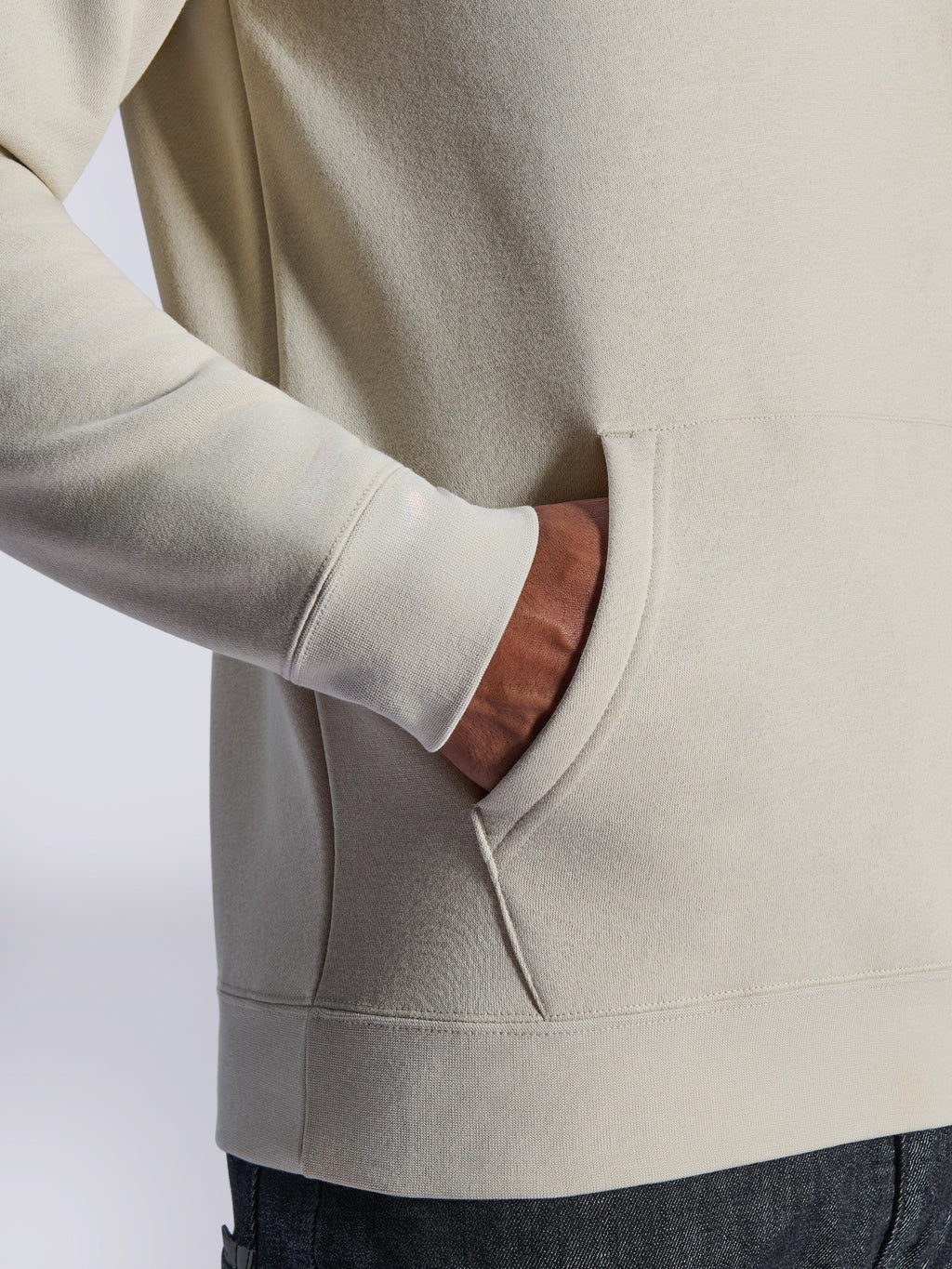 Sweat à capuche Alpinestars Ageless V3, détail en gros plan de la poche kangourou avant et du poignet côtelé, polaire blanc cassé, streetwear décontracté d'inspiration motorsport