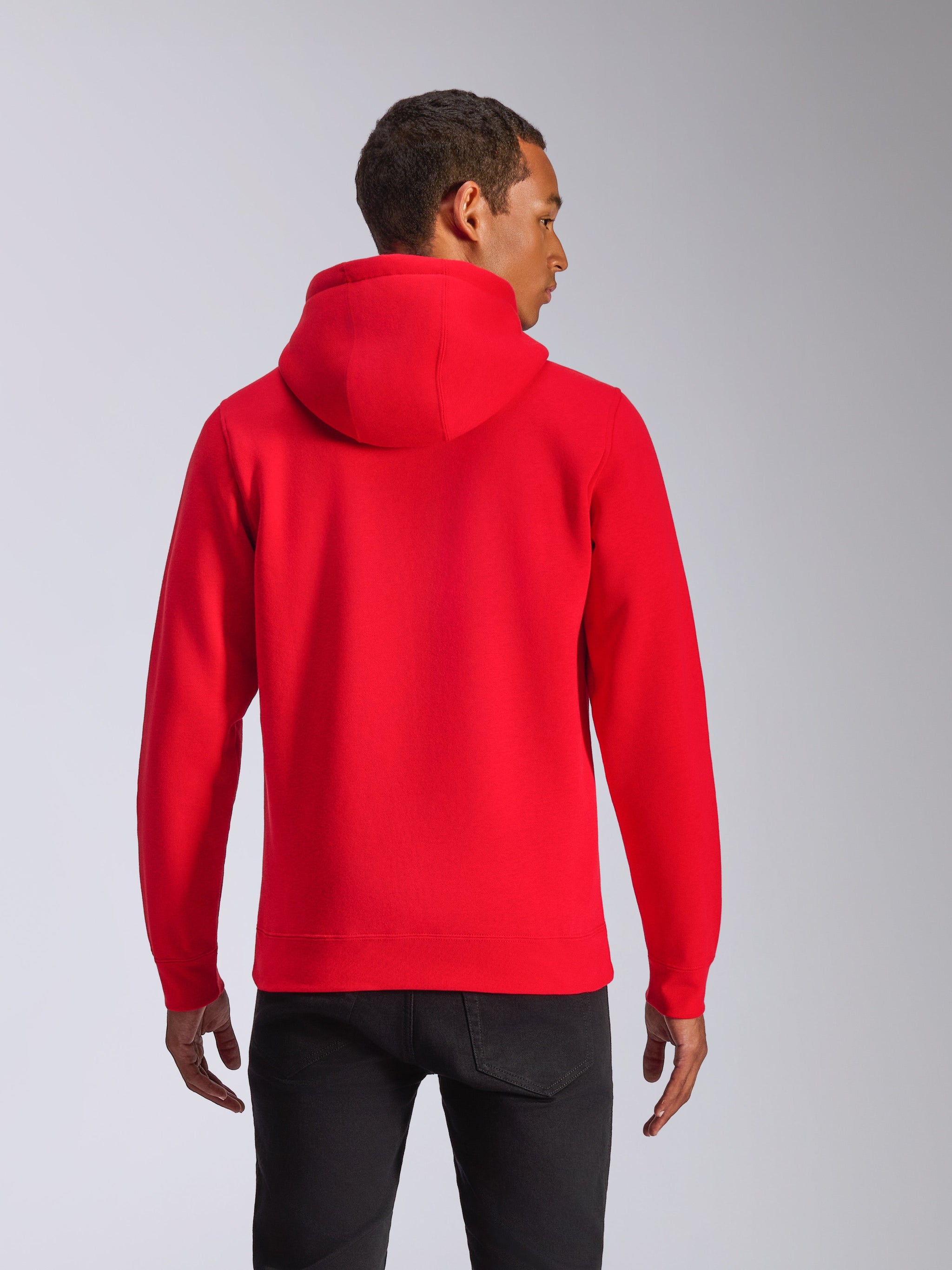 Sweat à capuche Alpinestars Ageless V3, vue de dos, sweat à capuche rouge, vêtement de sport décontracté doté d'une capuche doublée de jersey et de poignets côtelés, porté par un mannequin avec un pantalon noir